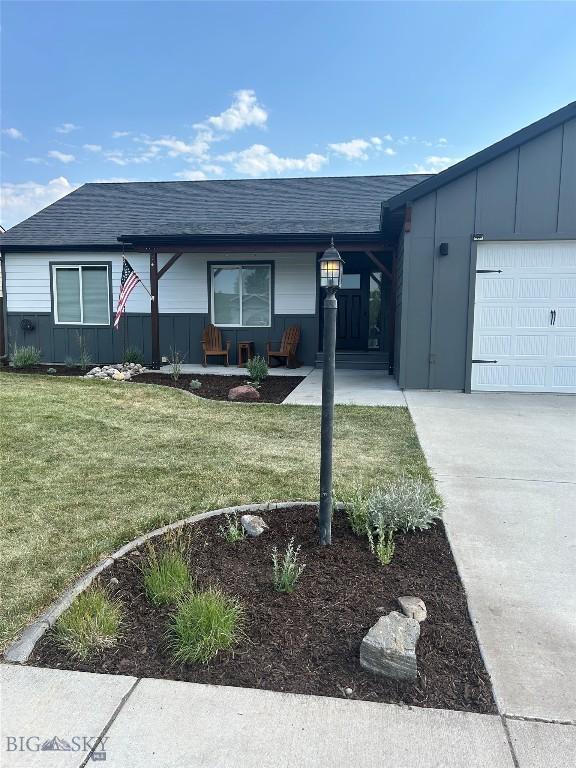 ranch-style house with an attached garage, concrete driveway, a front lawn, and roof with shingles