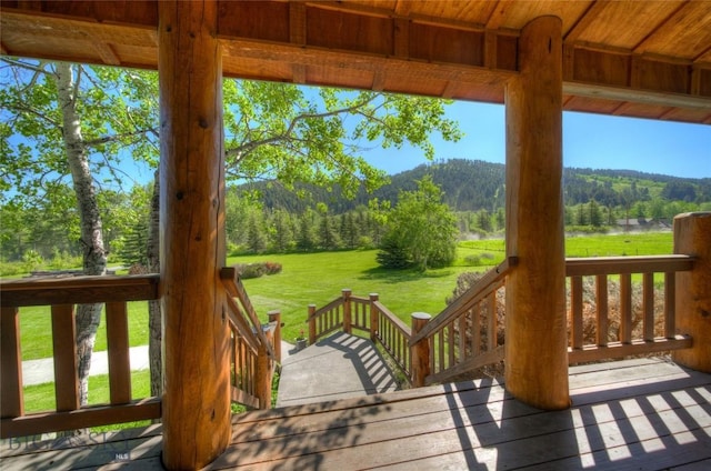 wooden terrace featuring a wooded view and a yard