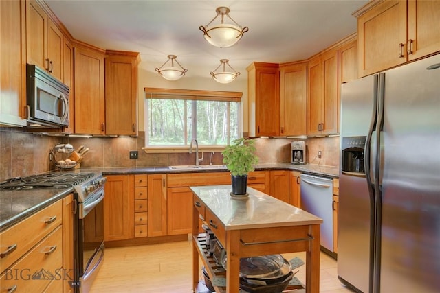 kitchen with a sink, stainless steel appliances, backsplash, and brown cabinetry