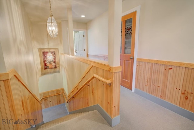 stairway featuring recessed lighting, wainscoting, wood walls, and carpet