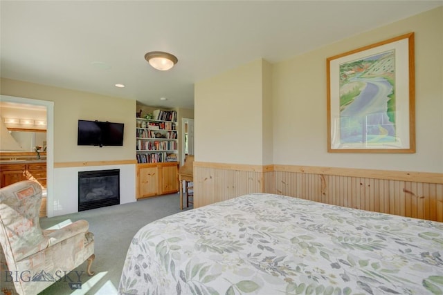 bedroom with a glass covered fireplace and carpet