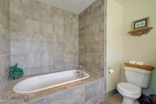 full bathroom with tile patterned floors, toilet, baseboards, and tiled bath