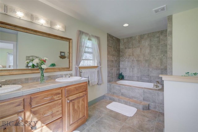 bathroom featuring tile patterned floors, a bath, visible vents, and a sink