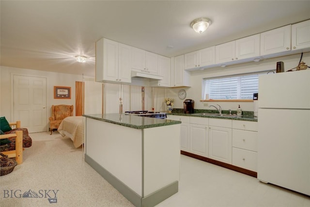 kitchen featuring a kitchen island, freestanding refrigerator, a sink, white cabinets, and under cabinet range hood