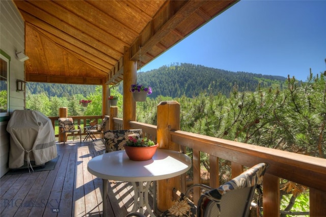 deck with grilling area and a view of trees