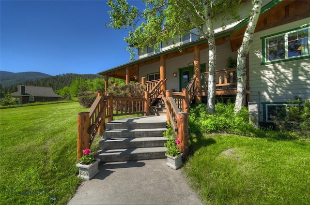 doorway to property with a mountain view, a lawn, and a porch