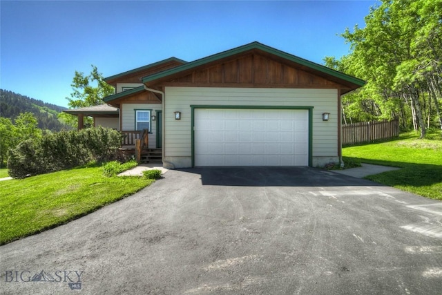 ranch-style home with aphalt driveway, a garage, a front lawn, and fence