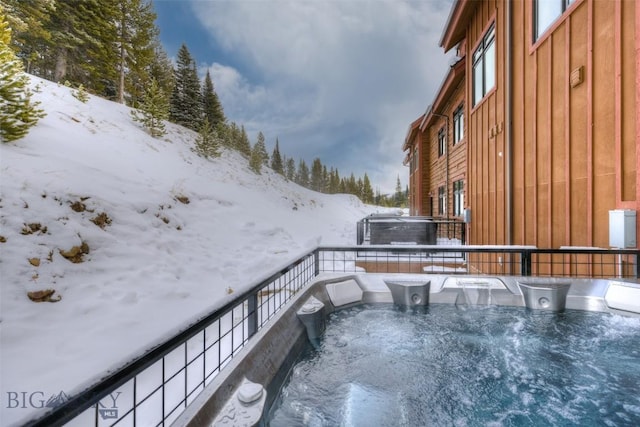 snow covered back of property featuring a hot tub