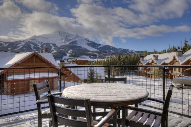 snow covered patio with a mountain view and a balcony