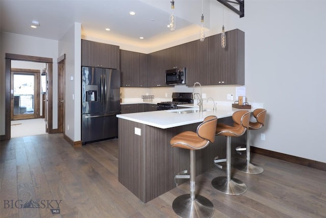 kitchen with fridge with ice dispenser, stainless steel microwave, a peninsula, light countertops, and gas range