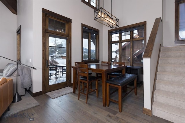 dining room featuring a healthy amount of sunlight, stairs, a high ceiling, and wood finished floors