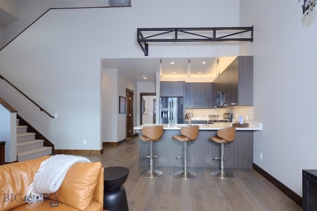 kitchen featuring dark wood-type flooring, a breakfast bar, appliances with stainless steel finishes, a peninsula, and light countertops