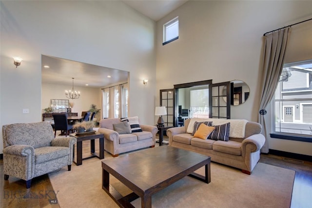 living room with visible vents, a notable chandelier, and a towering ceiling