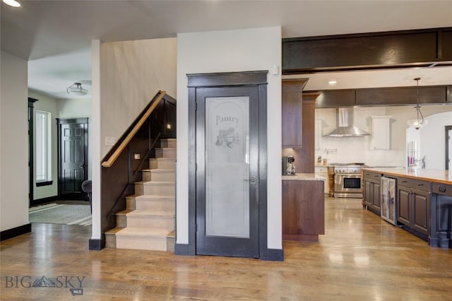 kitchen featuring wine cooler, light countertops, high end stainless steel range oven, wood finished floors, and wall chimney exhaust hood