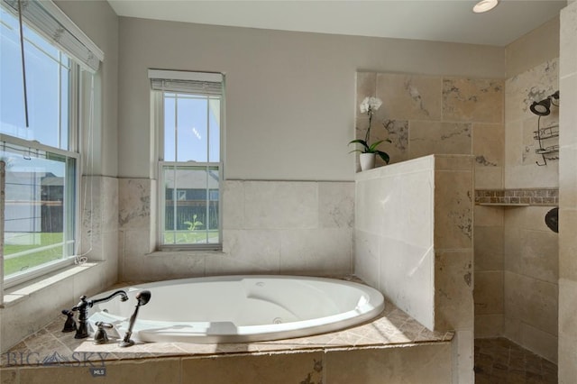 bathroom featuring a jetted tub, a walk in shower, and a wealth of natural light