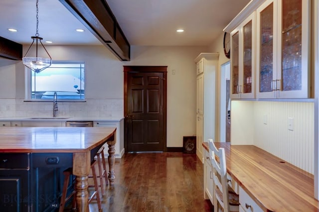 kitchen with decorative backsplash, butcher block counters, dark wood-style flooring, and a sink