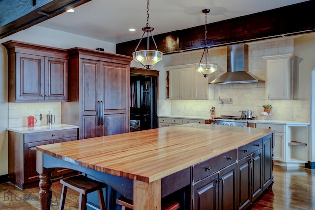 kitchen featuring white cabinets, wall chimney exhaust hood, and wood counters