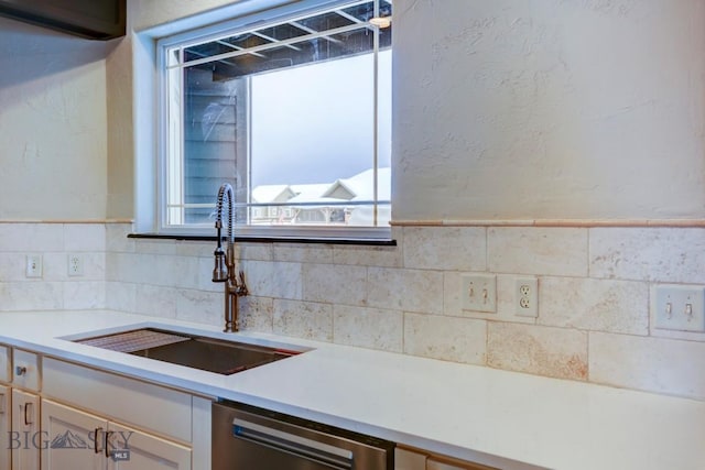 kitchen featuring dishwasher, light countertops, a textured wall, and a sink