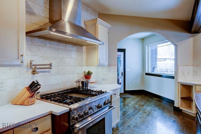 kitchen featuring high end range, backsplash, light countertops, and wall chimney range hood