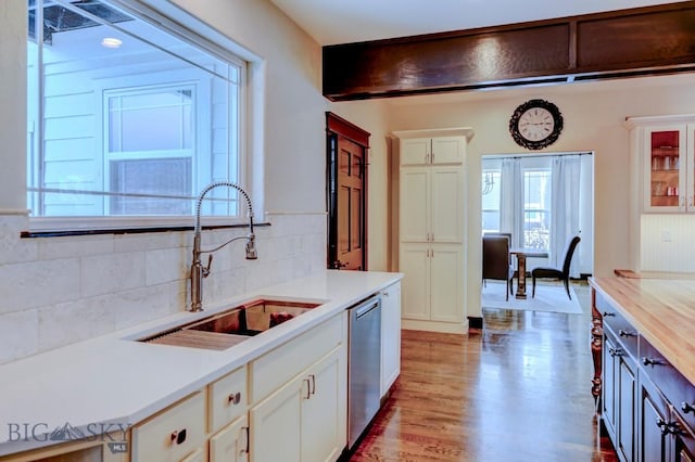 kitchen featuring dishwasher, light countertops, and a sink