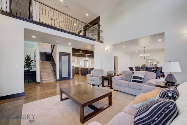 living room featuring wood finished floors, stairs, recessed lighting, a towering ceiling, and an inviting chandelier