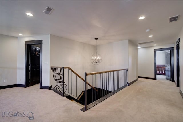 hall with baseboards, an upstairs landing, visible vents, and light carpet