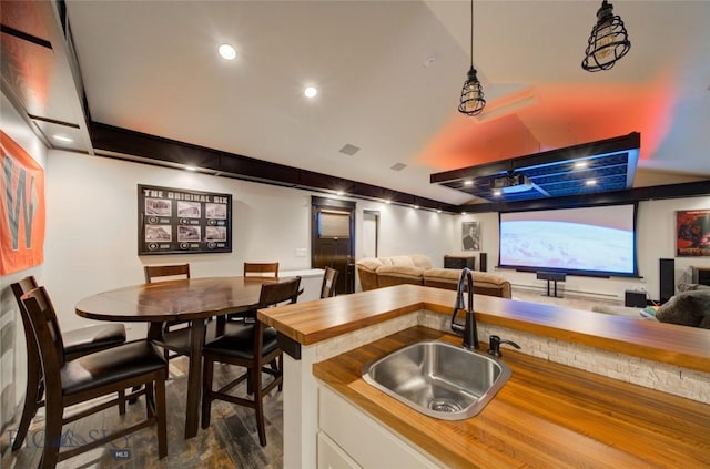 kitchen with wooden counters, recessed lighting, a sink, white cabinetry, and open floor plan