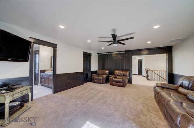 living room featuring wainscoting, recessed lighting, light colored carpet, and a barn door