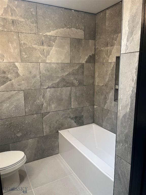 bathroom with tile patterned flooring, a tub, and toilet