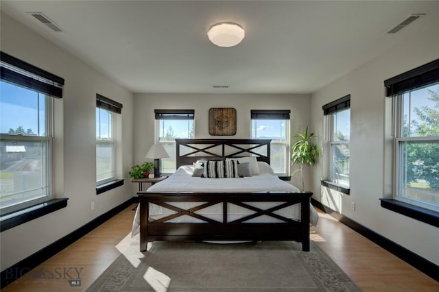 bedroom with visible vents, light wood-style flooring, baseboards, and multiple windows