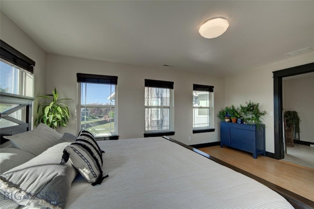 bedroom with visible vents, baseboards, and wood finished floors