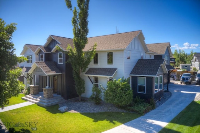 view of front of property with a front lawn, board and batten siding, and a shingled roof