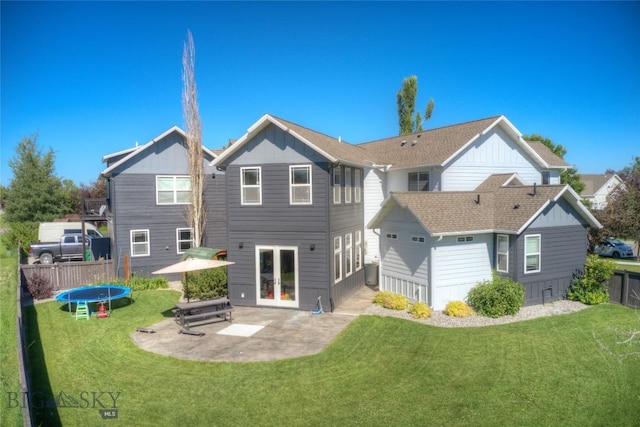 back of property with a lawn, a trampoline, fence, french doors, and a patio area