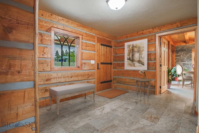 unfurnished room featuring rustic walls, a textured ceiling, and stone finish flooring