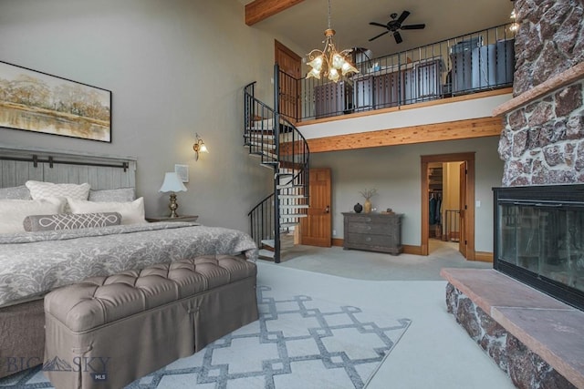 bedroom with beamed ceiling, carpet floors, a high ceiling, a stone fireplace, and a spacious closet