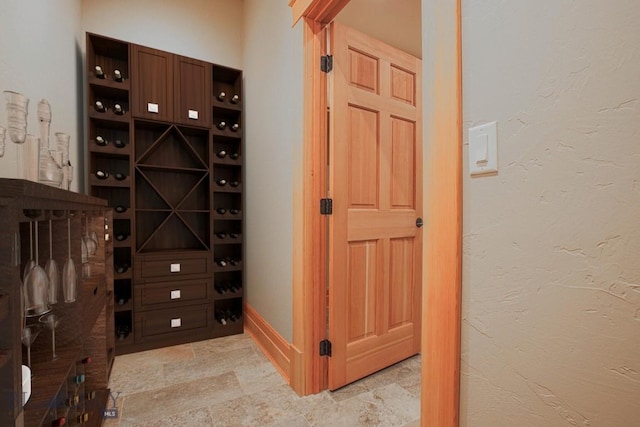 wine cellar featuring stone finish floor, a textured wall, and baseboards