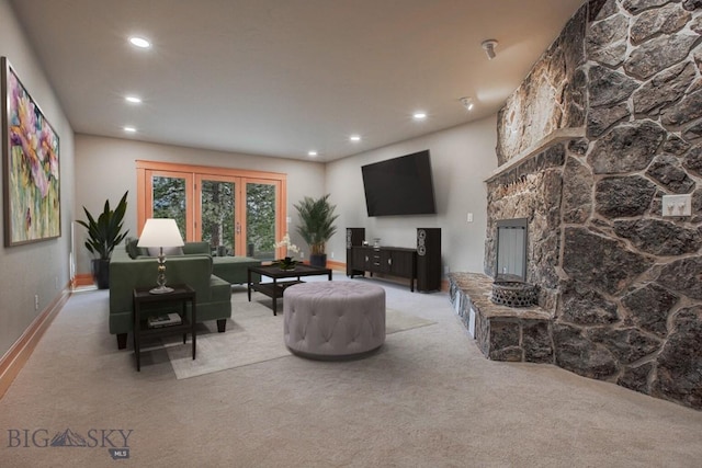 living area featuring recessed lighting, carpet floors, and a stone fireplace