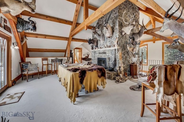 carpeted bedroom with a stone fireplace and lofted ceiling with beams