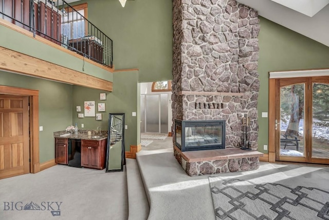 living area featuring a fireplace, high vaulted ceiling, baseboards, and carpet floors