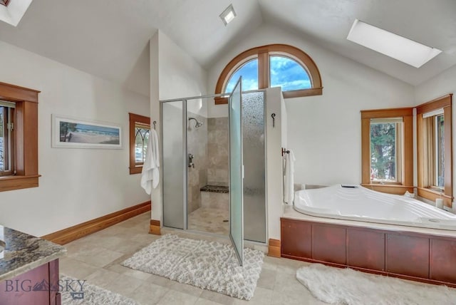 bathroom with vanity, a shower stall, vaulted ceiling with skylight, and a bath