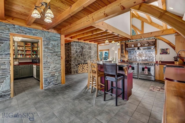 kitchen featuring dark tile patterned flooring, double oven range, wood ceiling, a kitchen breakfast bar, and a sink