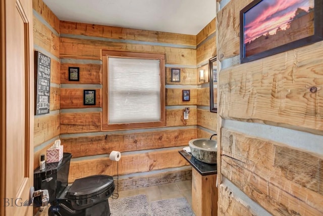 half bath featuring vanity, toilet, and wood walls