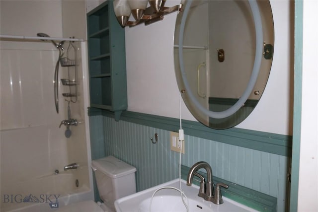 full bathroom featuring a wainscoted wall, toilet, bathing tub / shower combination, and a sink