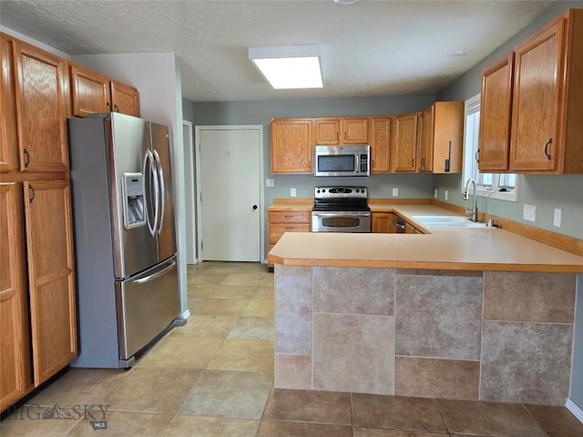 3004 Green Cir, Butte, MT 59701 - kitchen featuring appliances with stainless steel finishes, a sink, light countertops, a peninsula, and brown cabinetry