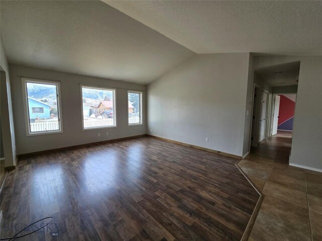 3004 Green Cir, Butte, MT 59701 - empty room with lofted ceiling, baseboards, dark wood-style flooring, and a textured ceiling