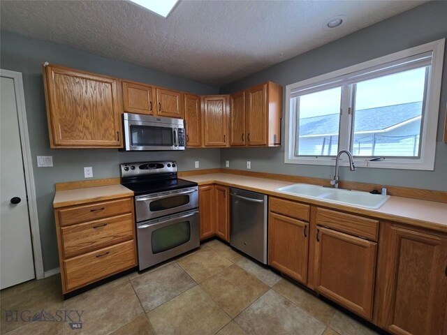 3004 Green Cir, Butte, MT 59701 - kitchen featuring appliances with stainless steel finishes, a sink, light countertops, a textured ceiling, and brown cabinets