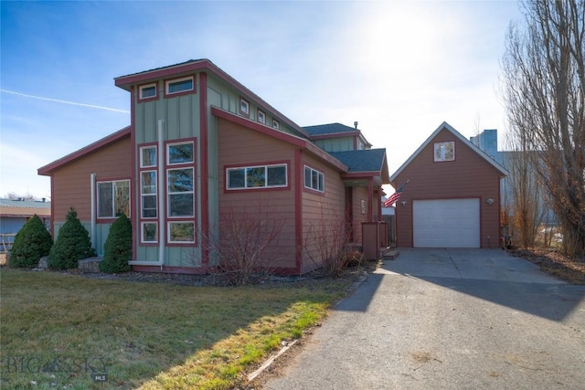 view of side of home featuring an outbuilding, a lawn, board and batten siding, and driveway