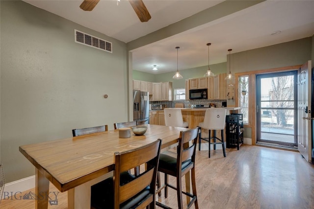 dining area with light wood-style floors, a healthy amount of sunlight, visible vents, and baseboards