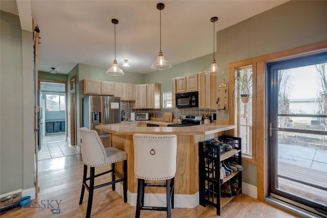 kitchen with light brown cabinets, decorative backsplash, appliances with stainless steel finishes, and light countertops