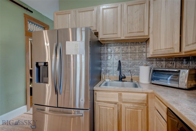 kitchen featuring stainless steel fridge, light brown cabinetry, and a sink